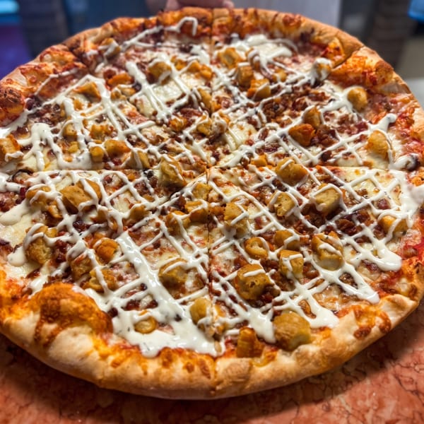 A whole buffalo chicken pizza, topped with crispy chicken, bacon, and a ranch drizzle.